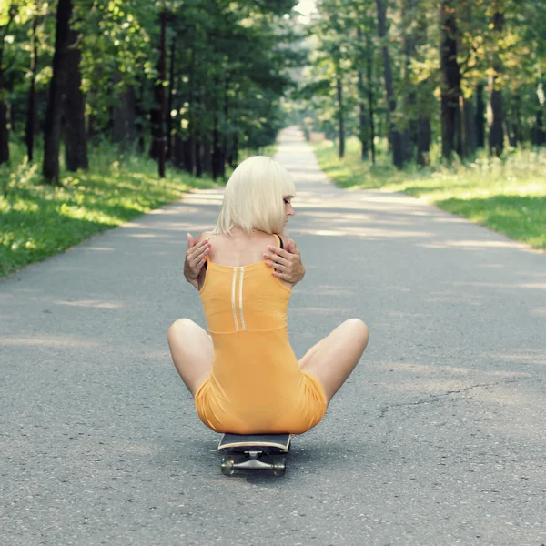 Meisje zit op skateboard — Stockfoto