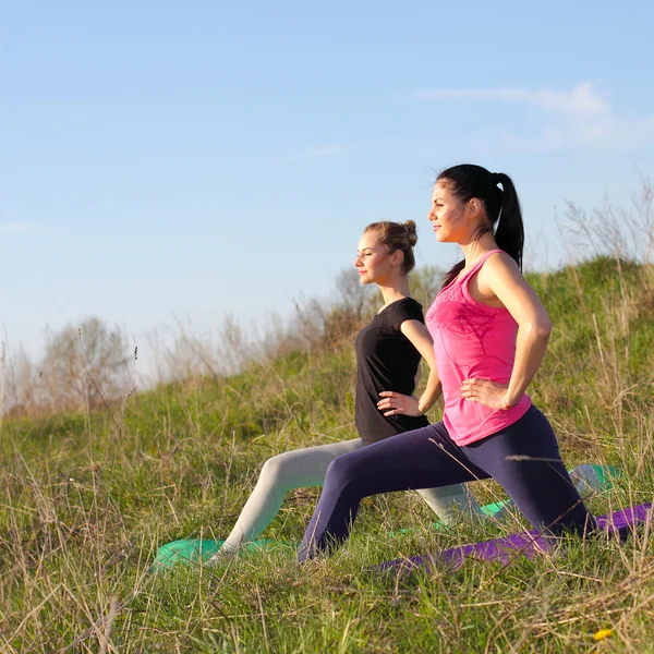 Two women doing yoga outdoors