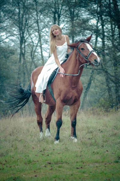 Ragazza in abito bianco su un cavallo nella foresta — Foto Stock