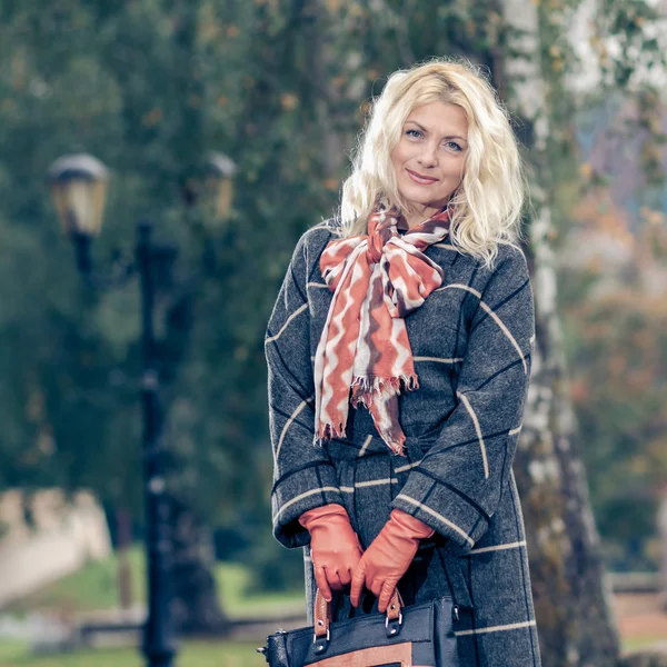 Mulher de casaco xadrez posando no parque — Fotografia de Stock