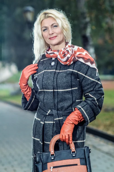 Kvinna i rutig kappa poserar i parken — Stockfoto