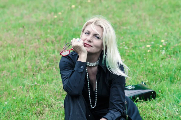 Женщина в черном костюме сидит на траве — стоковое фото