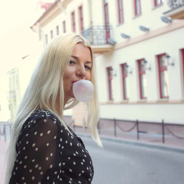 Blond girl blows bubblegum outdoors — Stock Photo, Image