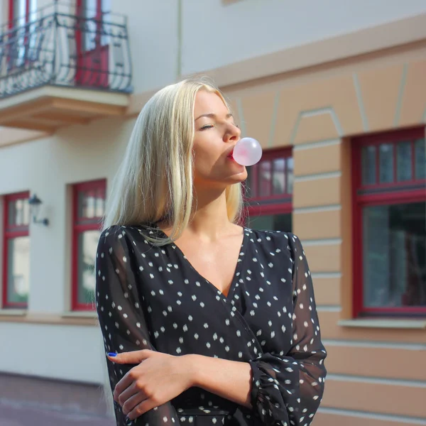 Blond meisje blaast bubblegum buitenshuis — Stockfoto