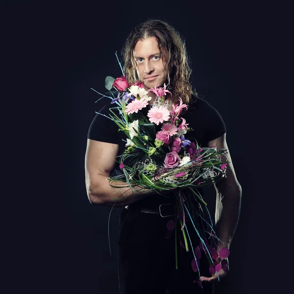 Muscular man holds a bouquet of flowers