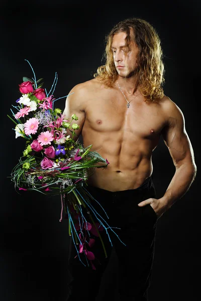 Manliga fitness modell bar överkropp håller en bukett blommor — Stockfoto