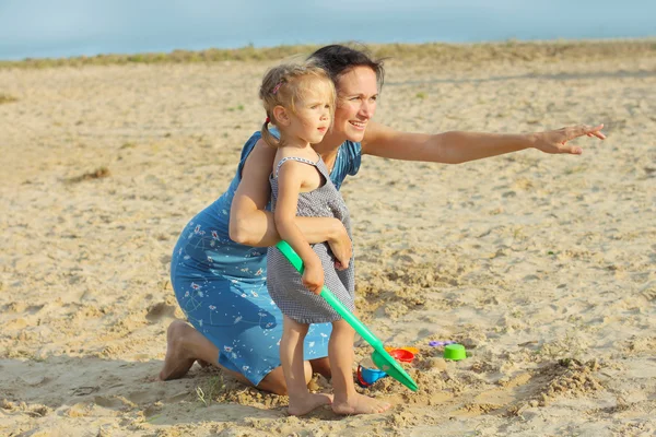 Мама с маленькой девочкой играет на пляже — стоковое фото
