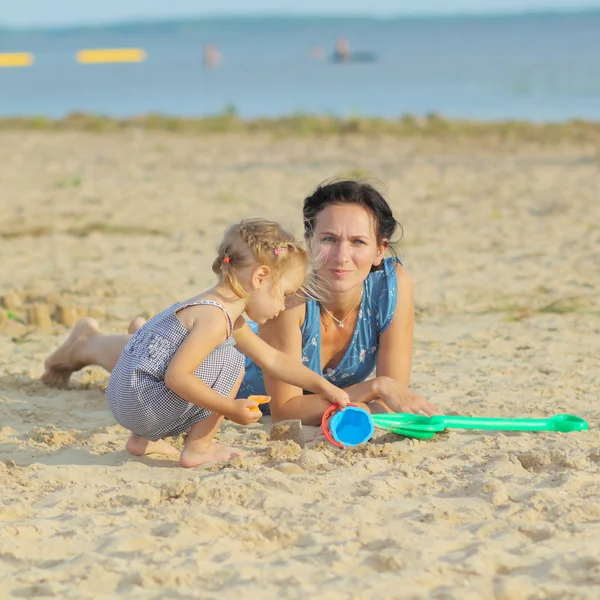 Mama z dzieckiem dziewczyna gra na plaży — Zdjęcie stockowe