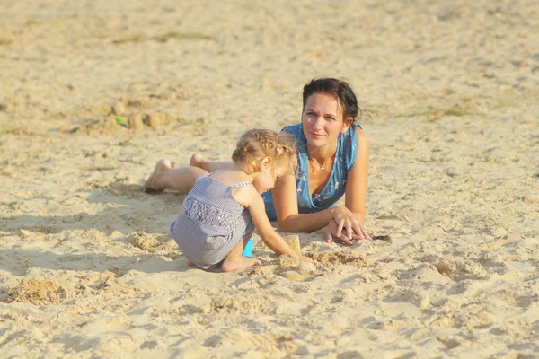 Мама с маленькой девочкой играет на пляже — стоковое фото