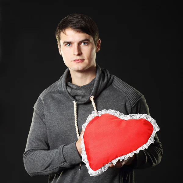 Man with a heart-shaped pillow. — Stock Photo, Image