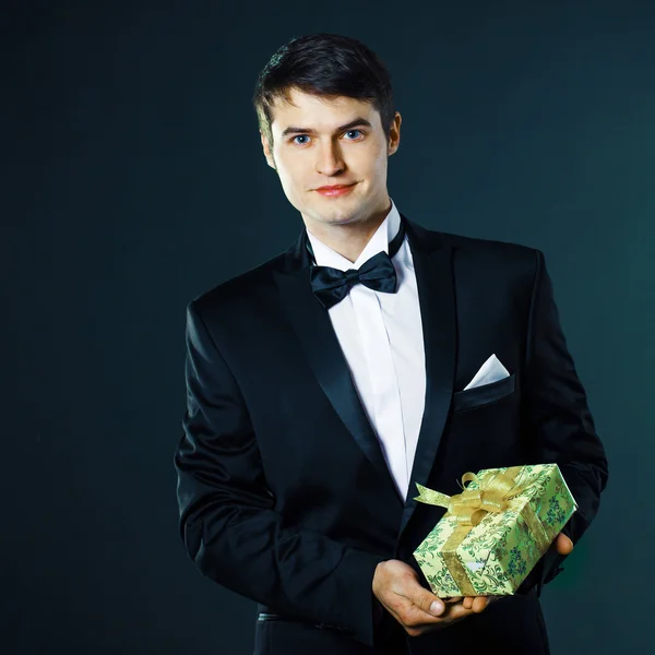 Man in a tuxedo gives a gift — Stock Photo, Image