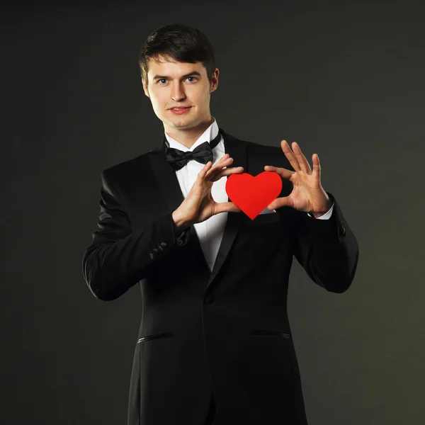 Man in een smoking met een rode papier hart — Stockfoto