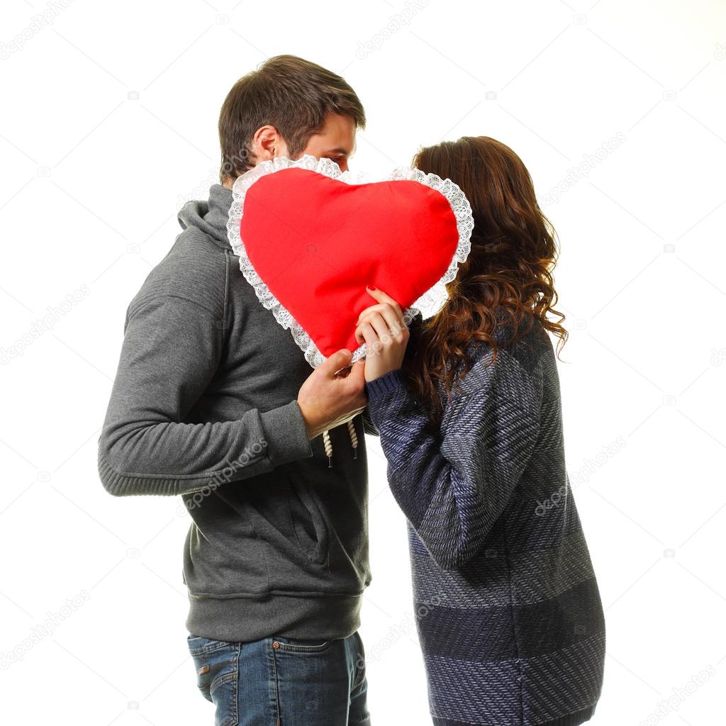 Young dates kissing behind heart