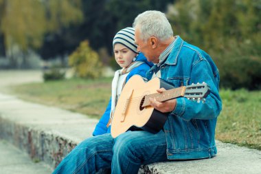 Grandfather and grandson playing guitar clipart