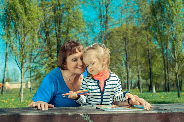 Grandmother and little granddaughter painting in nature — Stock Photo, Image