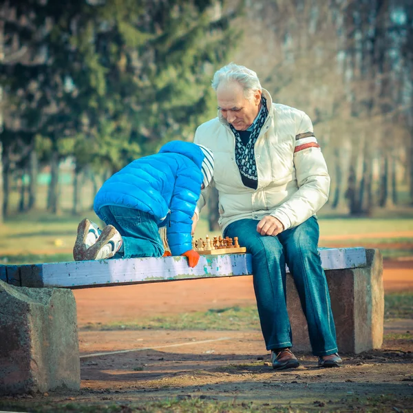 Дедушка и внук играют в шахматы — стоковое фото