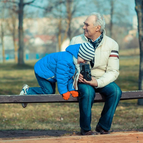 Grandfather shows grandson retro camera — Stock Photo, Image