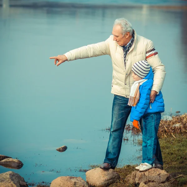 Großvater und Enkel auf den Flusssteinen — Stockfoto