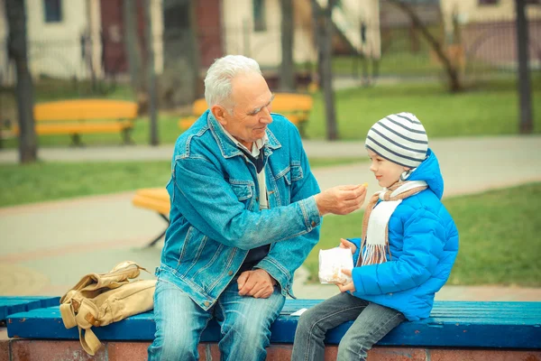 Дедушка и внук едят картошку фри — стоковое фото