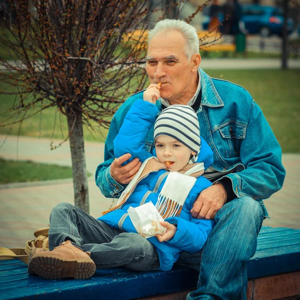 Дедушка и внук едят картошку фри — стоковое фото