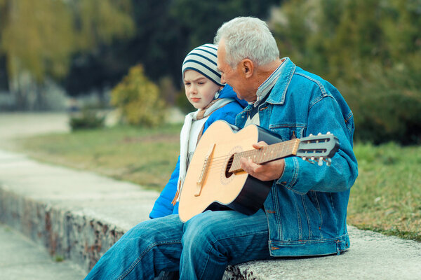 Grandfather and grandson playing guitar