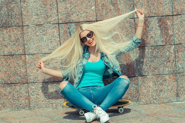 Flicka sitter på en skateboard — Stockfoto