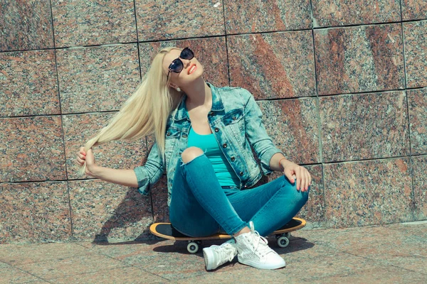 Mädchen sitzt auf einem Skateboard — Stockfoto