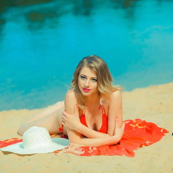 Sexy blonde bikini girl posing on beach. photo of a beautiful young woman with blowing hair relaxing on sand at a beach — Stock Photo, Image