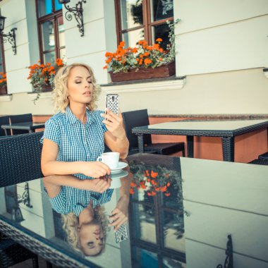 blond girl with phone in an outdoor cafe