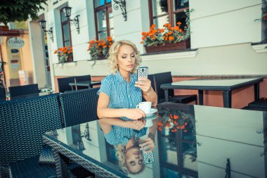 blond girl with phone in an outdoor cafe