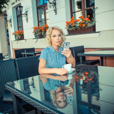blond girl with phone in an outdoor cafe