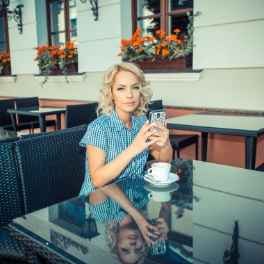 blond girl with phone in an outdoor cafe