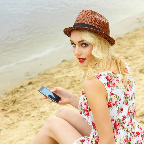 Vrouw op strand met smartphone — Stockfoto
