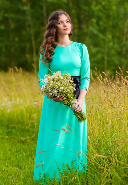 Mujer con ramo de flores en un campo — Foto de Stock