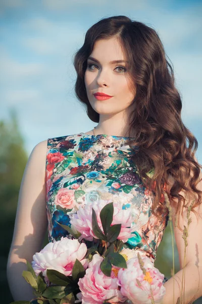 Mujer con ramo de flores en un campo — Foto de Stock