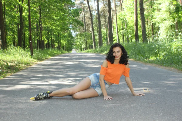 Femme en patins à roulettes, assise sur la route — Photo