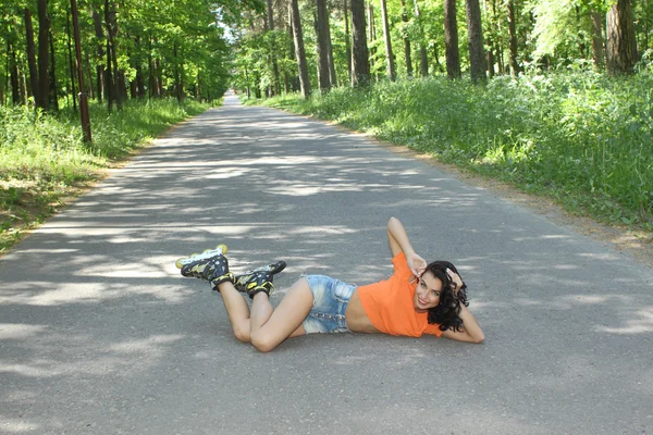 Žena na kolečkových bruslích, sedí na silnici — Stock fotografie