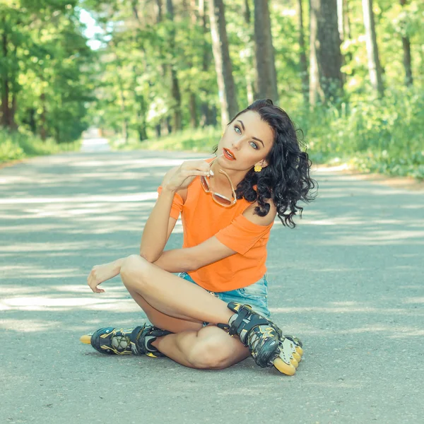 Vrouw in rolschaatsen, zittend op de weg — Stockfoto