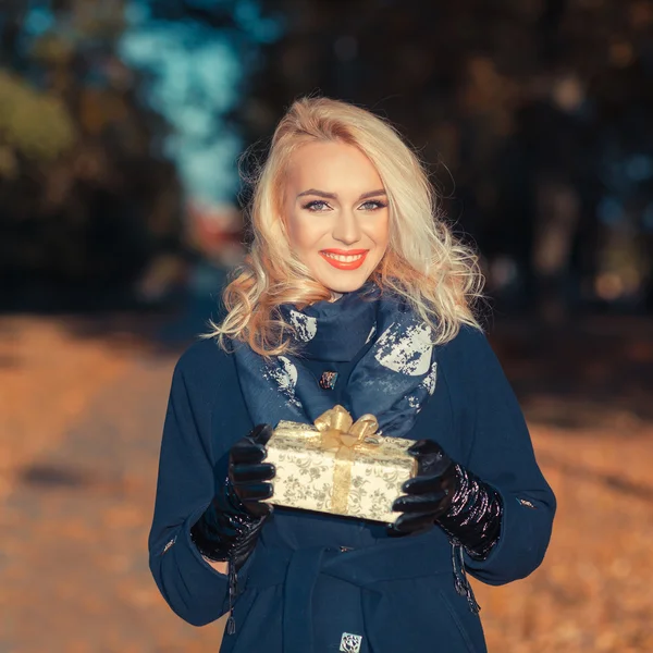 Happy woman with a gift in autumn park — Stock Photo, Image