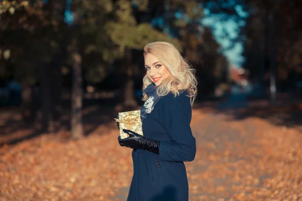 Mujer feliz con un regalo en el parque de otoño — Foto de Stock