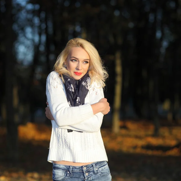 Блондинка в белом свитере в парке — стоковое фото