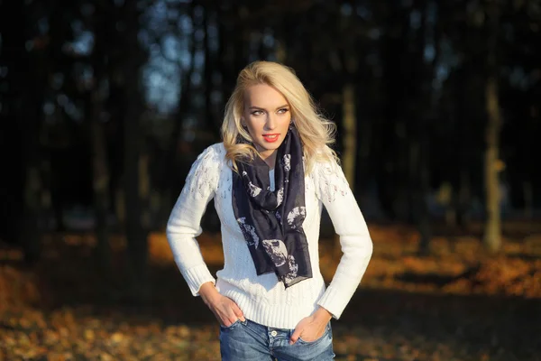 Блондинка в белом свитере в парке — стоковое фото