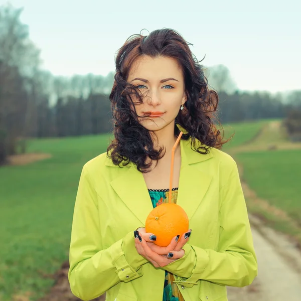 Mujer joven sosteniendo naranja, al aire libre — Foto de Stock