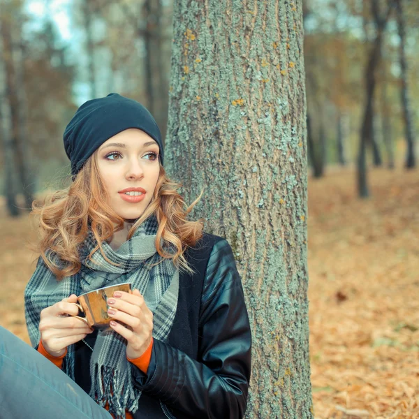 Žena s šálkem kávy v podzimním parku — Stock fotografie