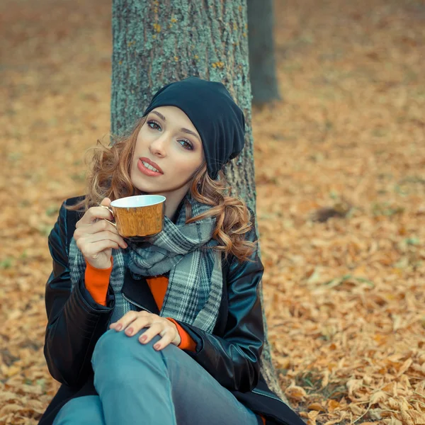 Žena s šálkem kávy v podzimním parku — Stock fotografie