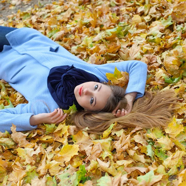 Flicka liggande bland gula blad — Stockfoto
