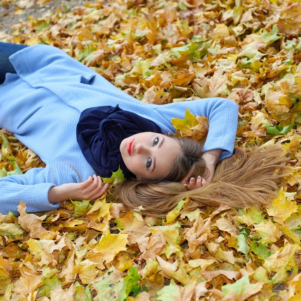 Fille couchée parmi les feuilles jaunes — Photo