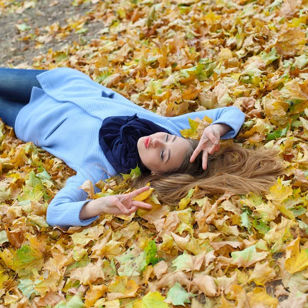 Girl lying among yellow leaves — Stock Photo, Image