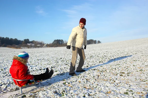 Dad pulling child on sled — Stock Photo, Image