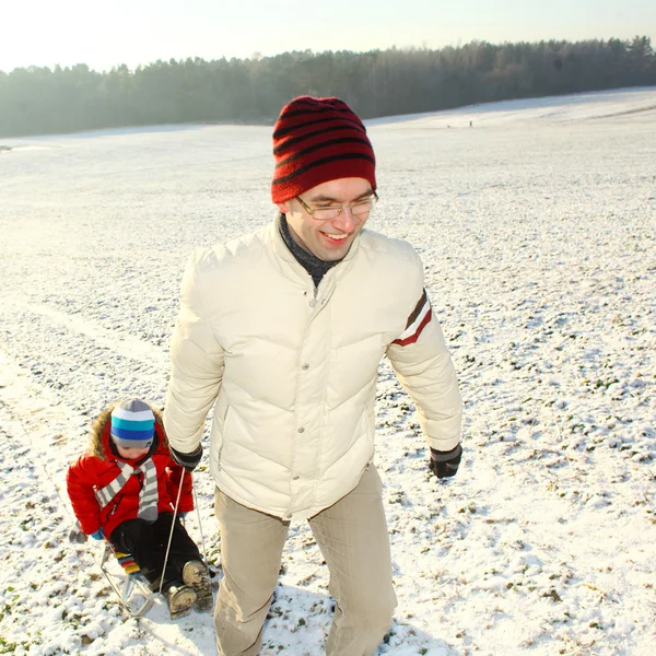 Dad pulling child on sled — Stock Photo, Image